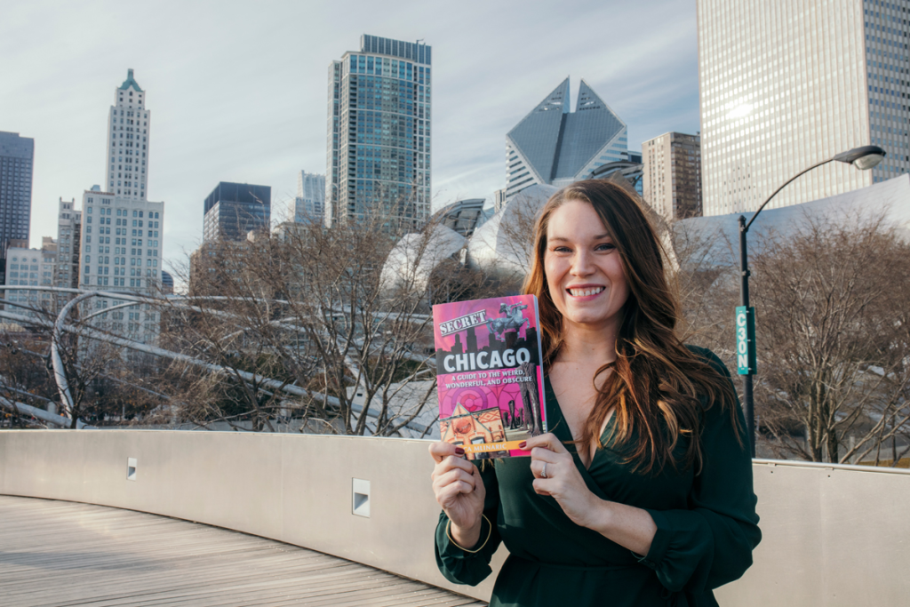 Jessica Mlinaric holds her book in front of the Chicago skyline